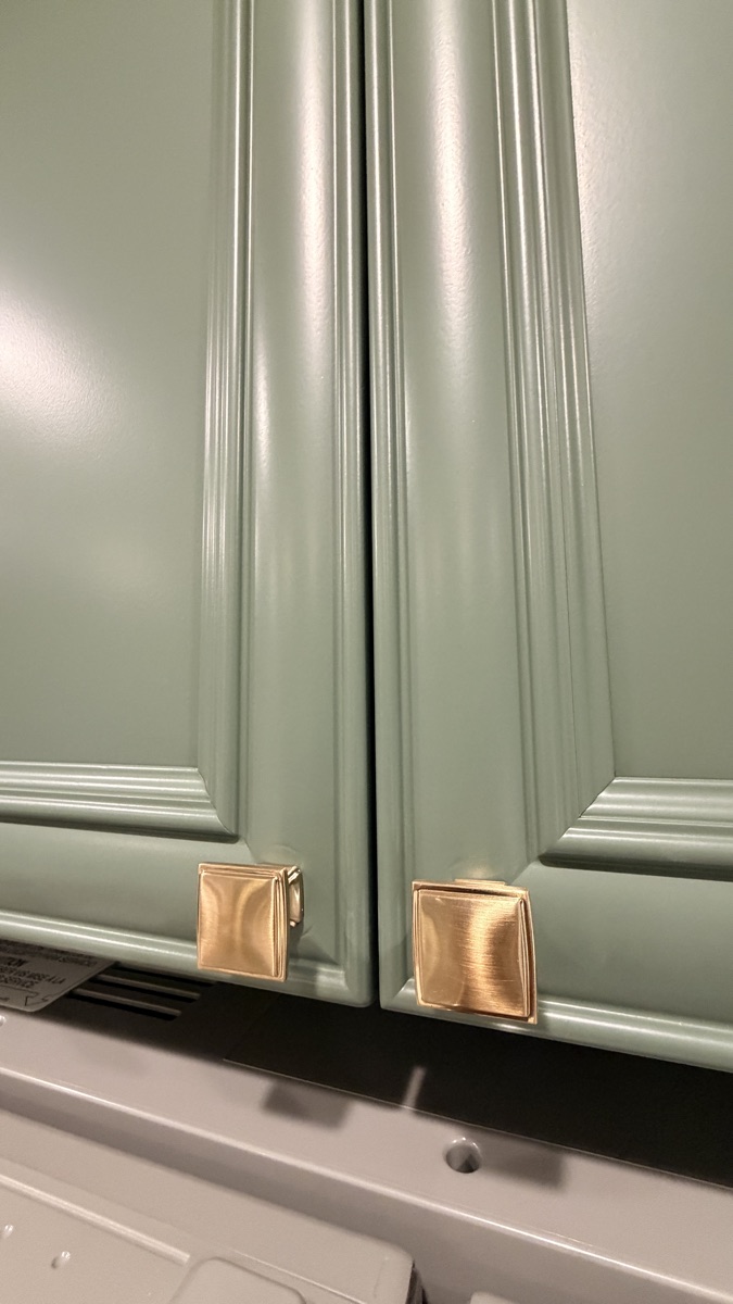 Close detail of Rosemary green cabinet color and brass hardware, a Cabinet Painting Guys client job