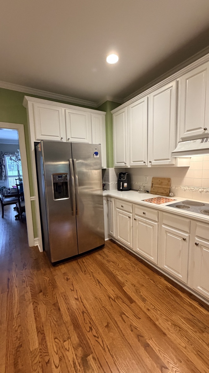 Real finished kitchen with White Flour painted cabinets around a stainless fridge, a Cabinet Painting Guys client job